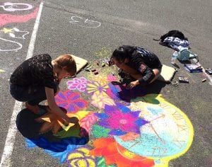 Two student-artists creating pavement chalk art