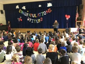"Congratulations Writers" banner in cafeteria with students seated