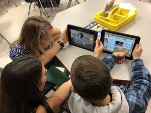 Teacher with two students viewing videos on ipads