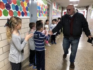 Bus driver high-fives students in hallway