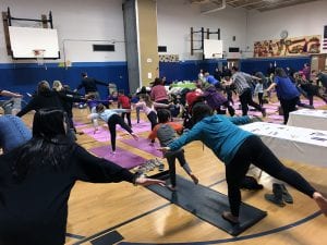 Families doing yoga pose in gym