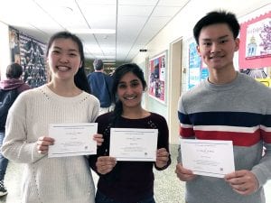 Three students standing with certificates