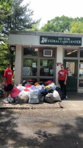 A male and a female student with bags of donations outside animal shelter