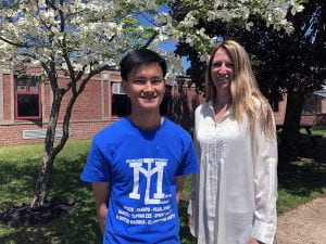 Student standing under flowering tree with principal