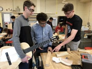 Students in wood shop with guitar
