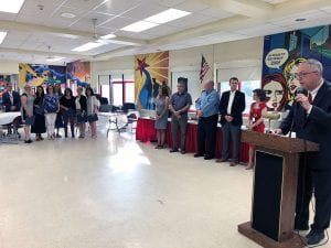 Staff, administrators standing with superintendent at podium