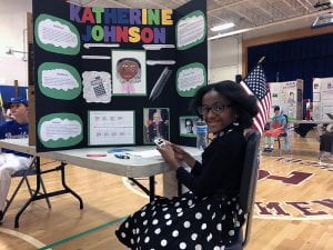 Student dressed as Katherine Johnson with trifold presentation board
