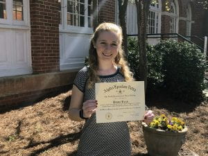 Female holding certificate on a sunny day in front of brick building