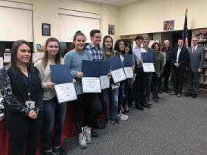 District administrators, board members and students holding certificates standing in line