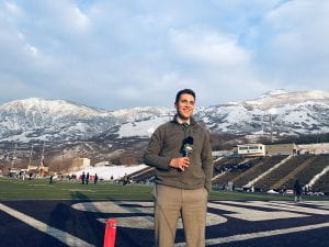Andrew Badillo with mic at sports event with snowy mountains in background