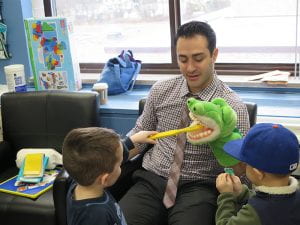 Dentist using puppet to show kids how to brush teeth
