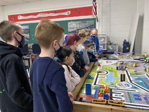 Students and advisor watch robot on game table