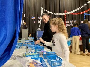 TZHS student helps WOS student at Penguin Patch sale
