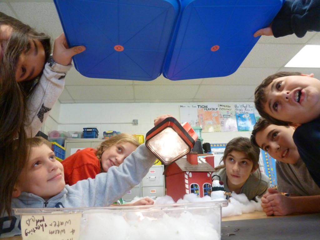 When the classroom light is turned off, the students could see the light of the flashlight reflect off the snow and shine on the bottom of the trays.