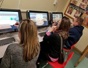 Three SOMS parents, seated, explore virtual reality educational technology