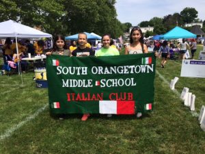 Four students hold South Orangetown Middle School Italian Club Banner at relay race