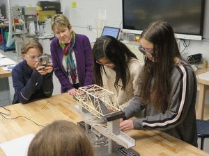 Teacher and students looking at bridge on structure tester