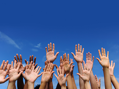 Cluster of hands raised against blue sky